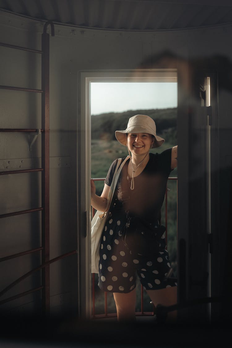 A Woman In Brown Shirt Standing At The Doorway