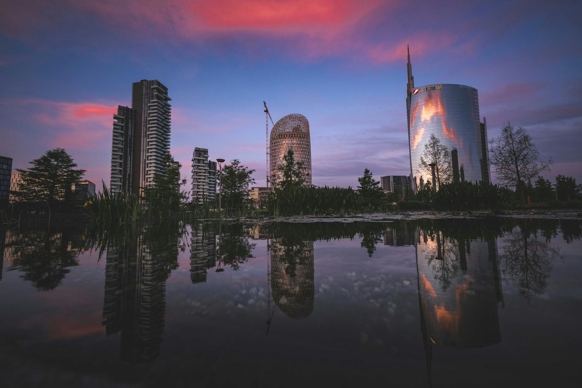 Stunning view of Milan's skyline reflected in water with sunset colors enhancing the scene.