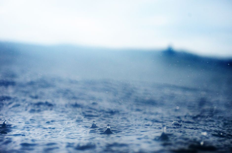 Calm ocean with raindrops creating ripples under a cloudy sky, Mar del Plata, Argentina.
