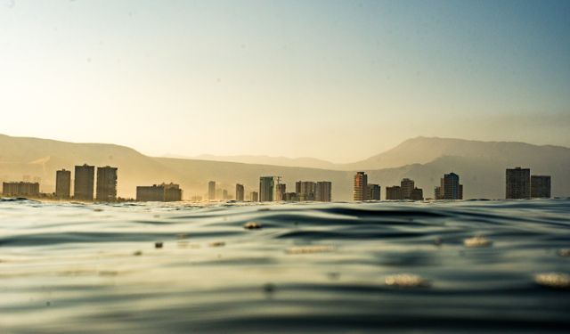 Captivating view of a distant coastal city skyline from the ocean at sunset.
