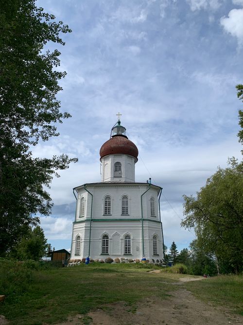 Free Charming white church with a red dome surrounded by lush greenery under a blue sky. Stock Photo
