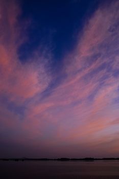 Stunning sunset view with dramatic cloudy sky reflecting over a calm ocean surface, perfect outdoor photography scene.