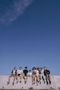 Group of Young People Sitting on a Wall under Blue Sky