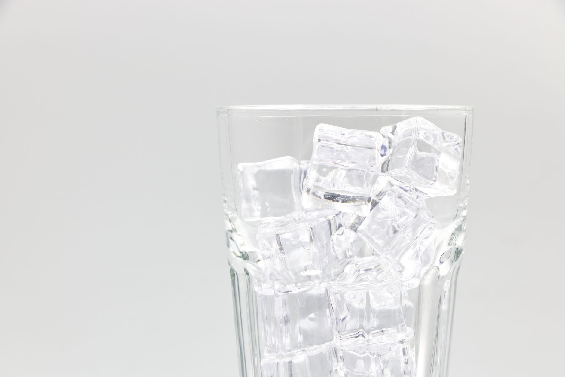 Close-up of a glass filled with ice cubes on a white background.