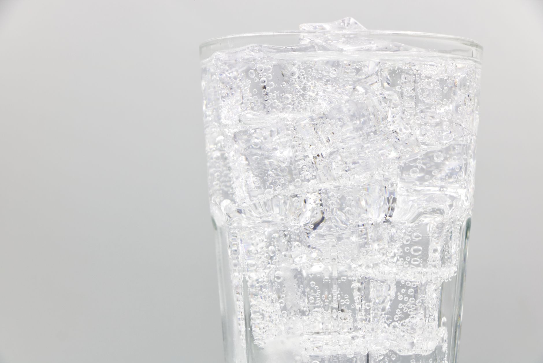 Close-up of a glass filled with sparkling water and ice cubes, ideal for refreshing summer drinks.