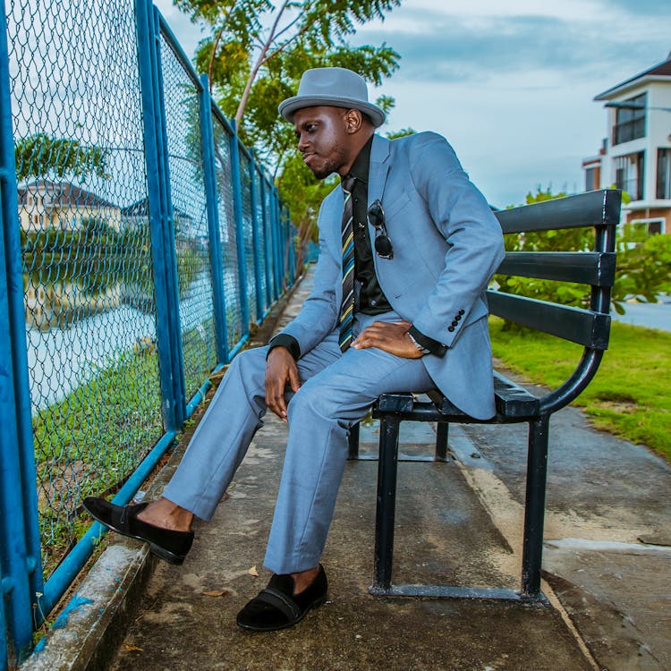 Man In Blue Suit Sitting On A Bench