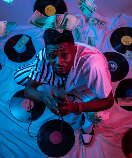 Free Dynamic portrait of a musician with a microphone, surrounded by vinyl records and flying cash, showcasing vibrant energy. Stock Photo