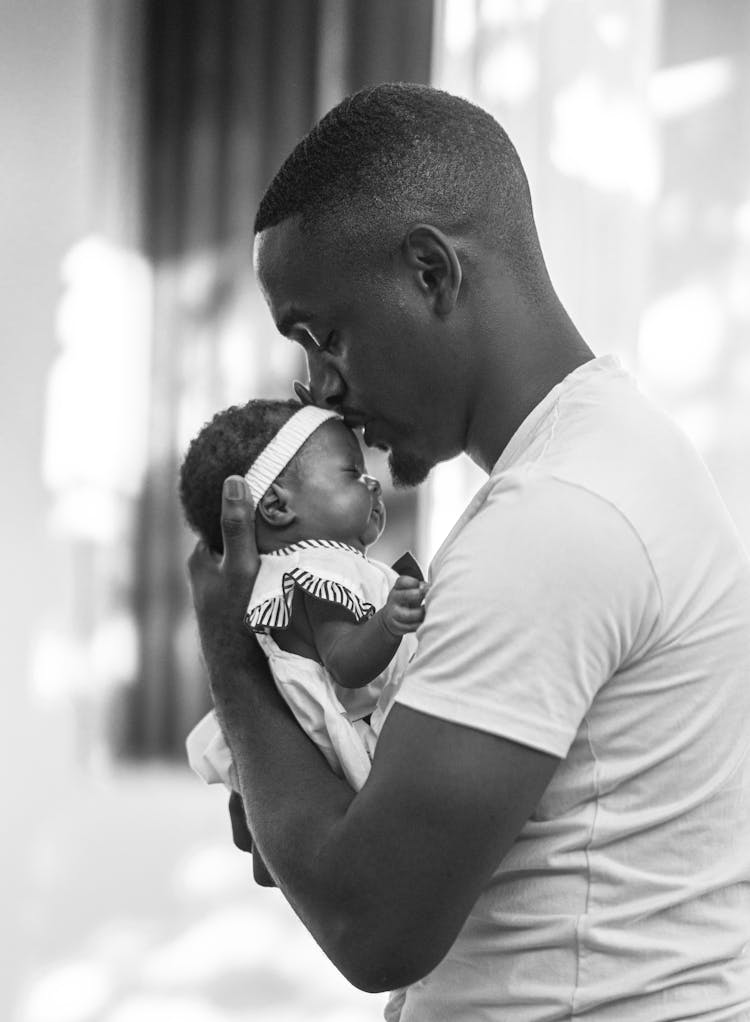 Grayscale Photo Of A Man In White Shirt Carrying His Baby 