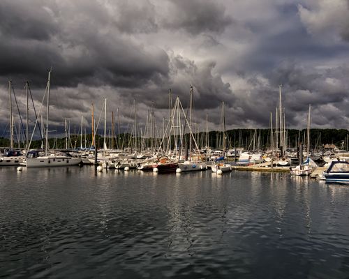 Free Sailboats docked in a German marina beneath a sky filled with dramatic clouds. Stock Photo