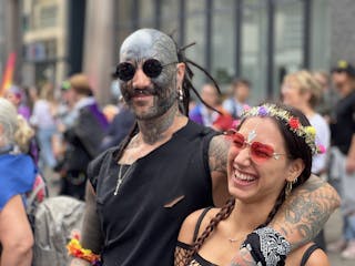 A Tattooed Man Standing Beside the Smiling Woman with Flower Headband