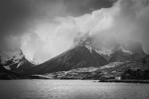 Grayscale Photo of Cloudy Mountains near Ocean