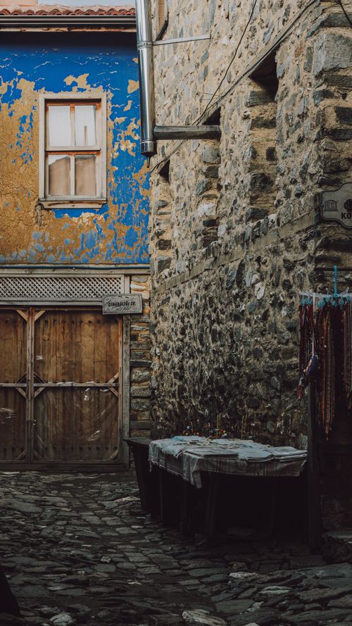 Free Atmospheric alleyway showcasing rustic architecture, featuring a peeling blue facade and cobblestone path. Stock Photo