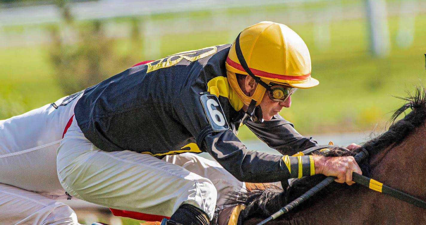 Jockey concentré en pleine action sur son cheval de course, visage tendu par l'effort