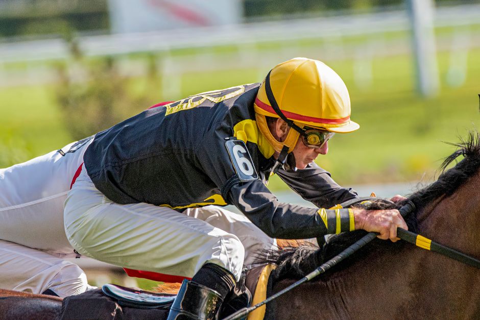 A close-up of a jockey focusing intensely while racing his horse, showcasing speed and agility.