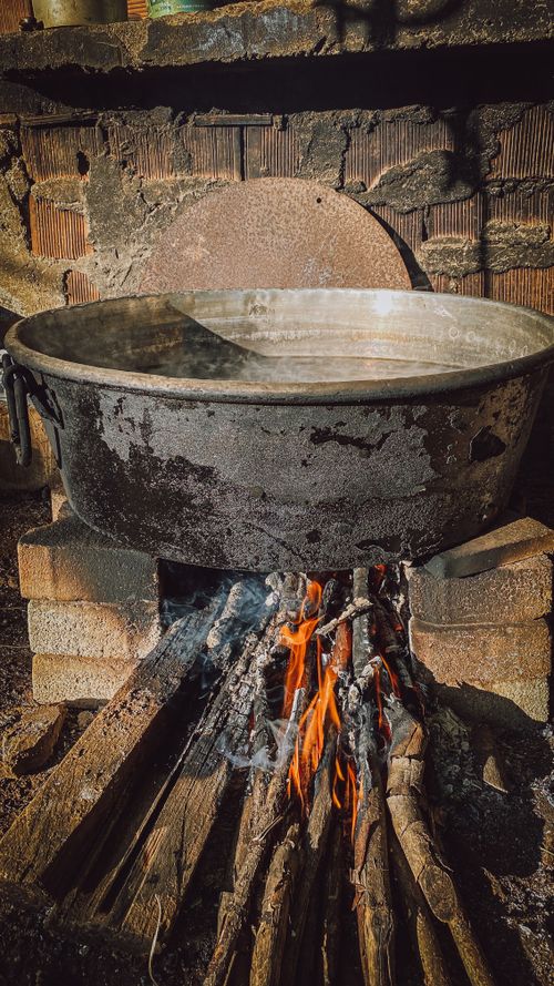 Free Rugged metal pot on firewood flames for authentic outdoor cooking experience. Stock Photo