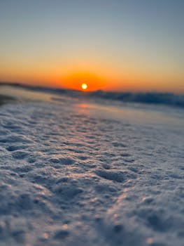 Captivating sunrise over the ocean with foamy waves in the foreground. Perfect seascape scene.