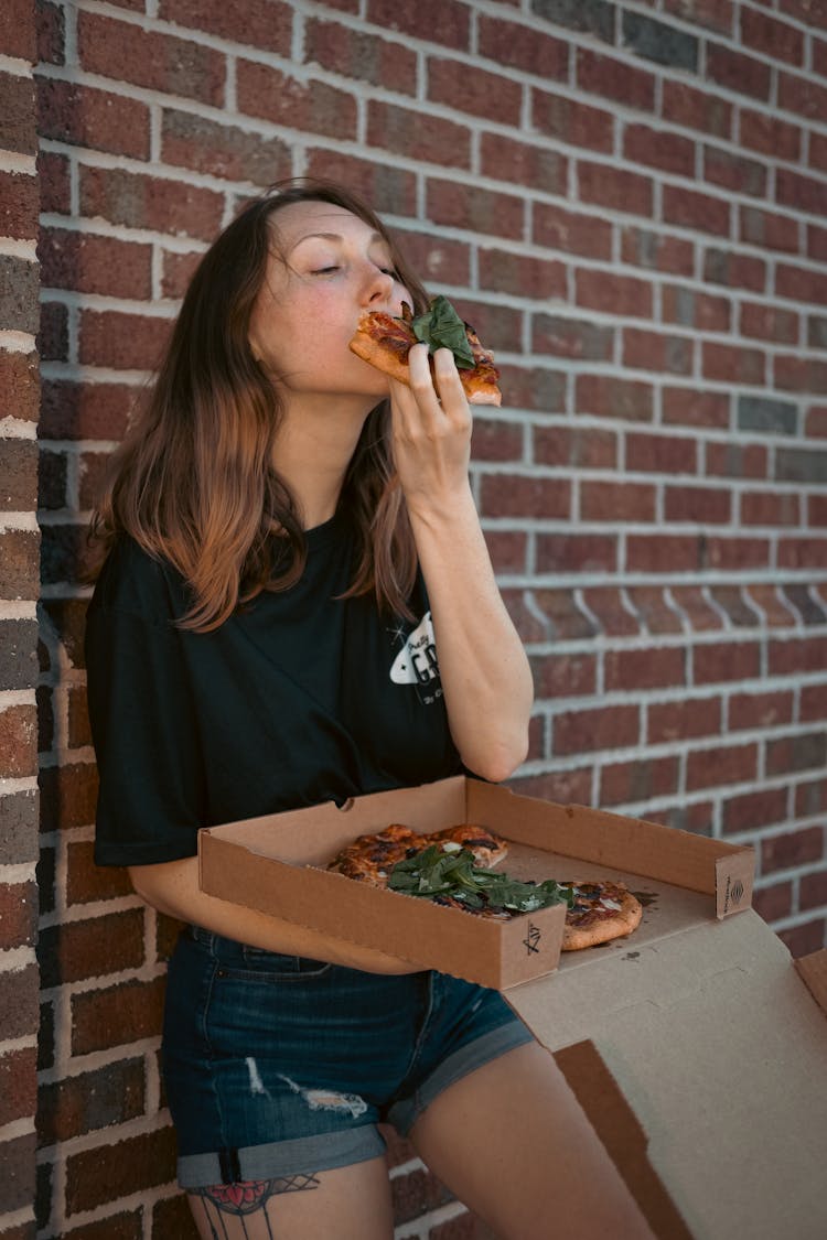 A Woman Eating A Slice Of Pizza 