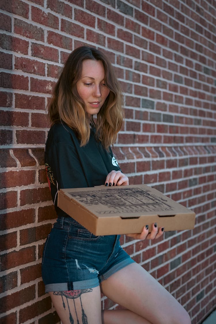 A Woman Holding A Box Of Pizza