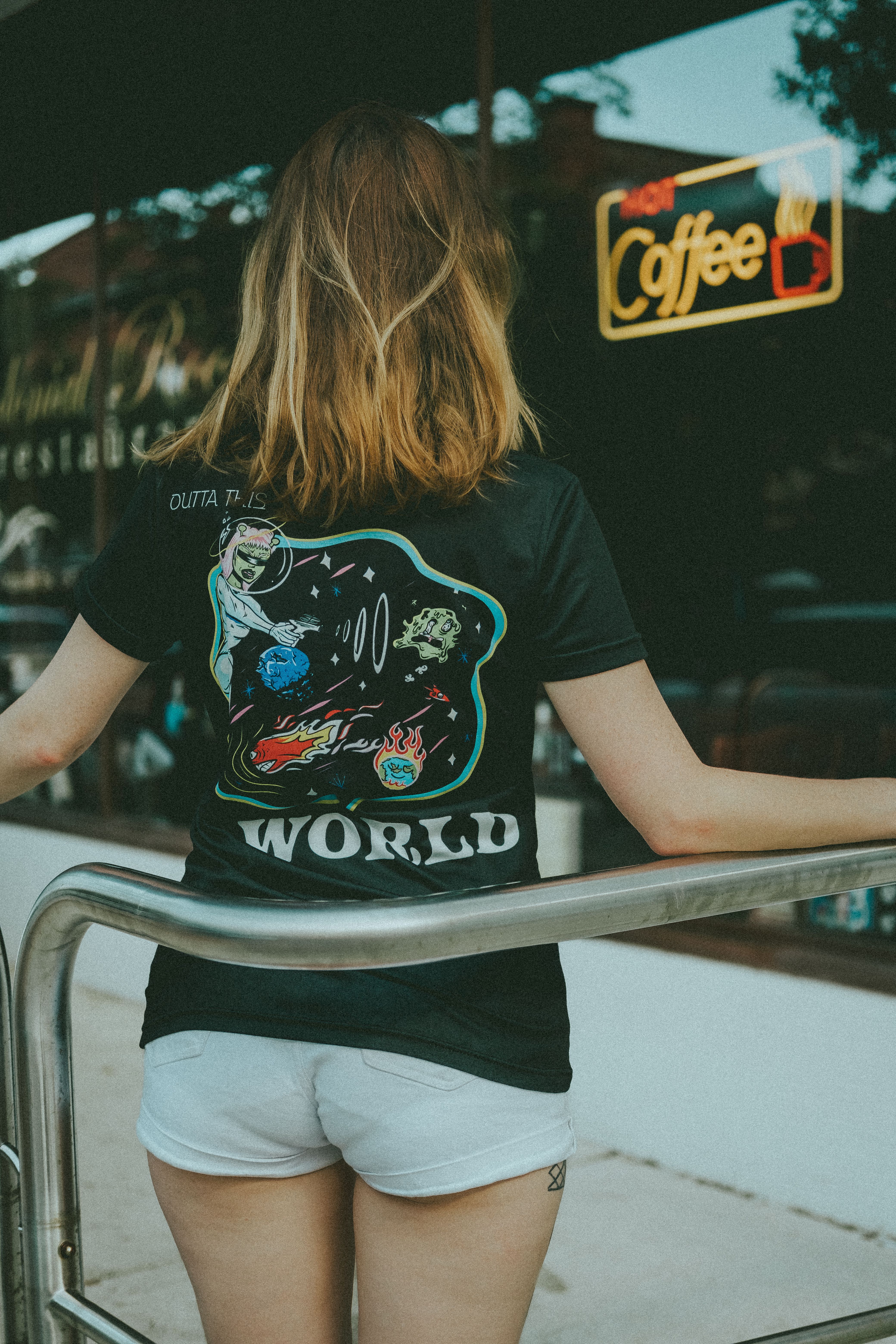Casual scene showing a woman with print shirt in summer city setting, back view.
