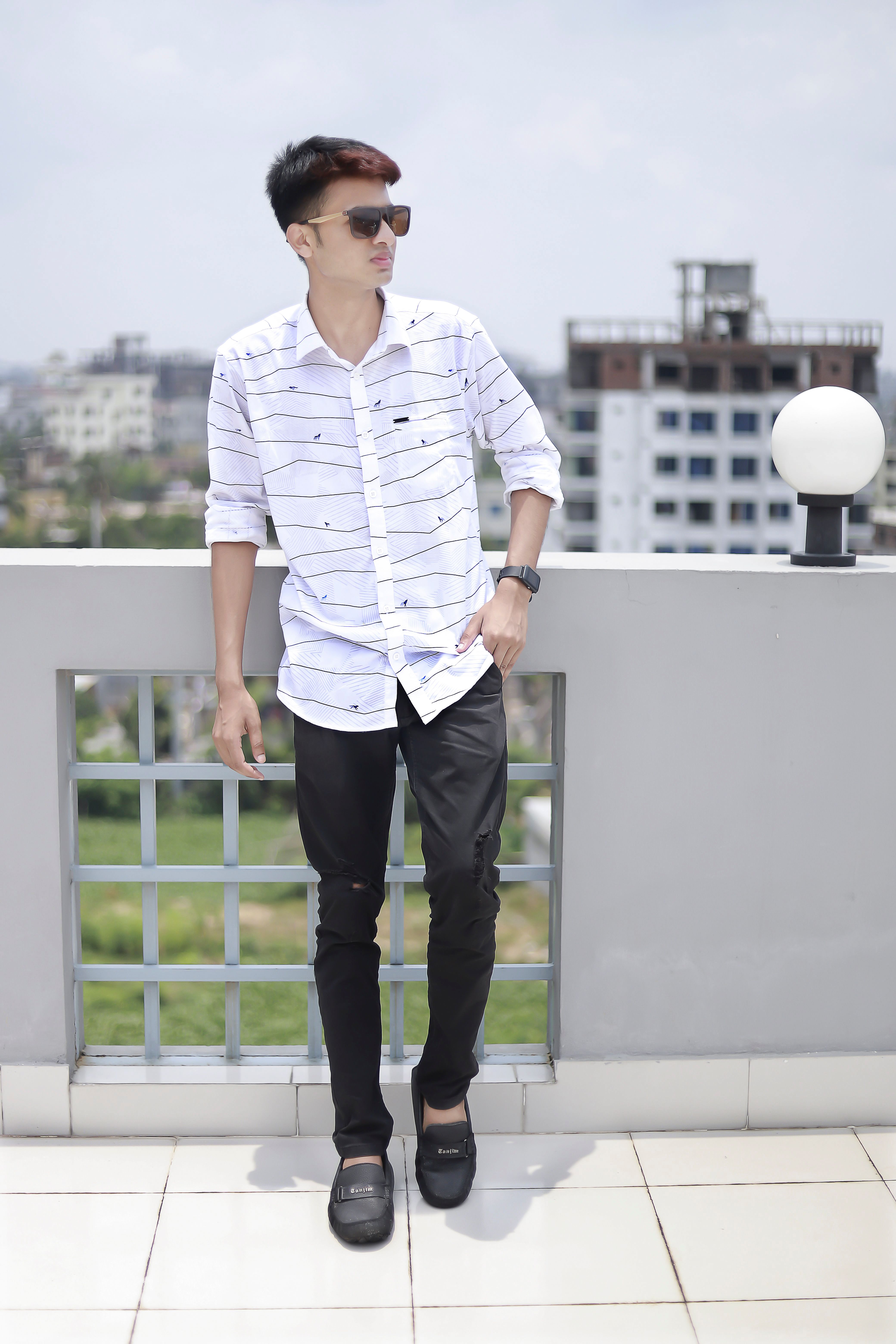 Young man in sunglasses and casual attire posing on a rooftop in Dhaka, Bangladesh.