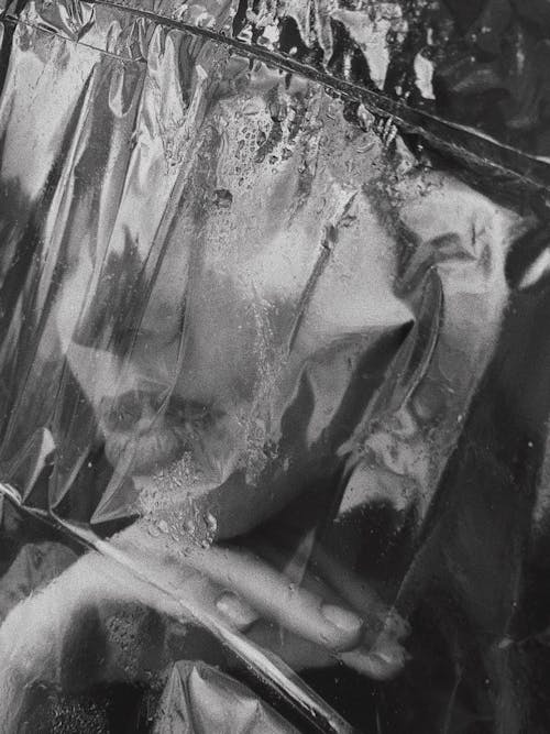 A Grayscale of a Woman Covered with a Plastic