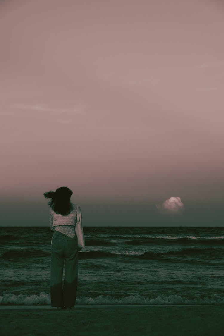 Back View Of A Woman Standing On The Sea Shore Under The Sky