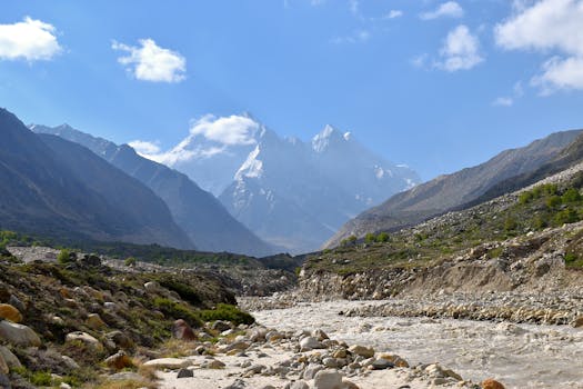 Explore the breathtaking Gangotri Valley with flowing rivers and majestic mountains under a clear blue sky.