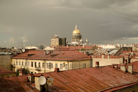 View of St. Petersburg rooftops with St. Isaac's Cathedral under a stormy sky.