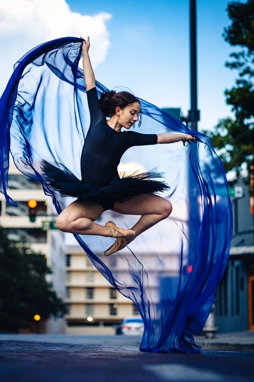 Free A ballerina elegantly leaps mid-air with a flowing scarf against a city backdrop in Orlando. Stock Photo