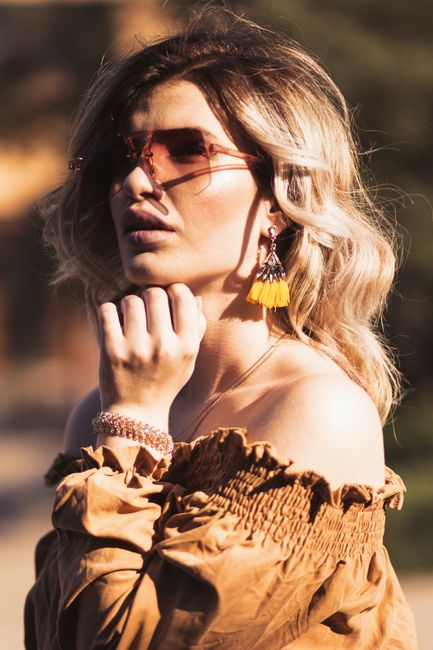 Stylish woman in sunglasses posing outdoors with elegant fashion accessories in summer.