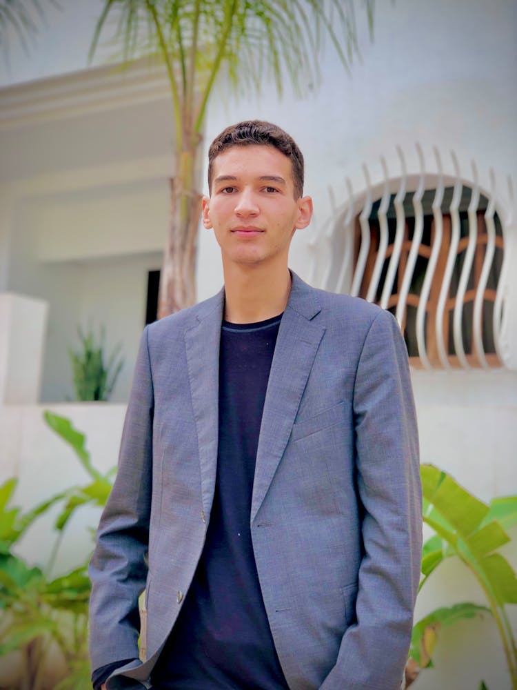 Young Man Wearing A Suit Posing In Front Of A White Building