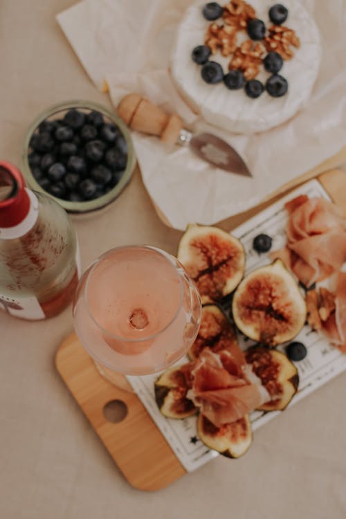A Delicious Drink in a Wine Glass Beside Slices of Fig Fruits on a Wooden Chopping Board