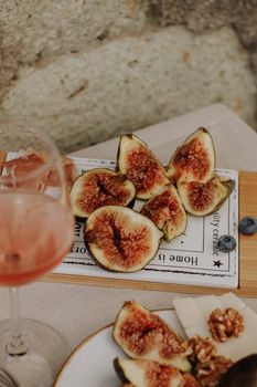 A rustic arrangement of fresh figs, wine, and cheese with walnuts and blueberries.