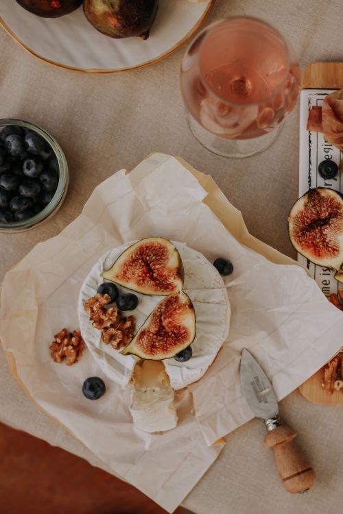 Free A delicious arrangement of brie cheese topped with fresh figs, blueberries, and walnuts on a rustic table setting. Stock Photo