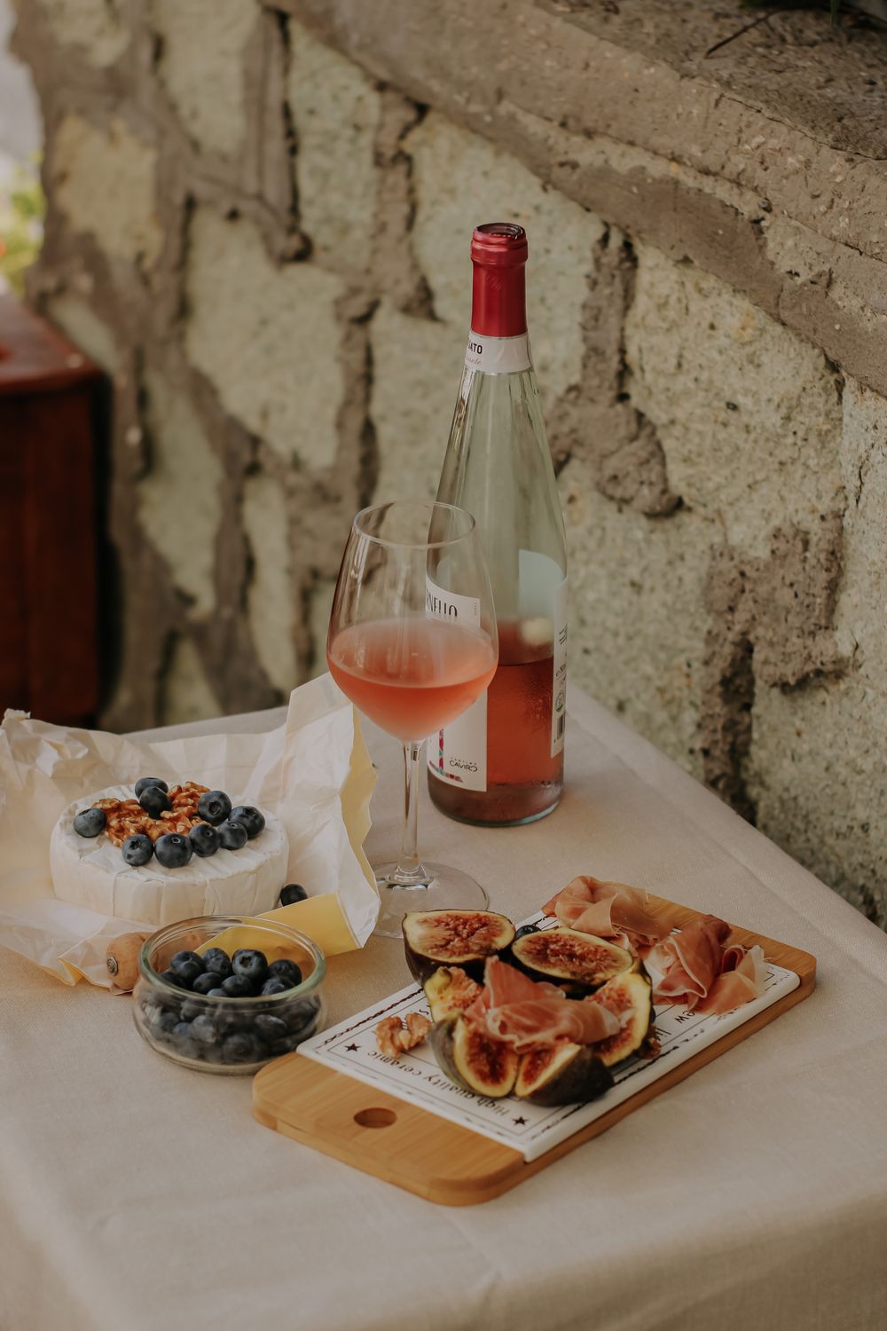Een sfeervol gedekte tafel met kaas, fruit en een glas rosé