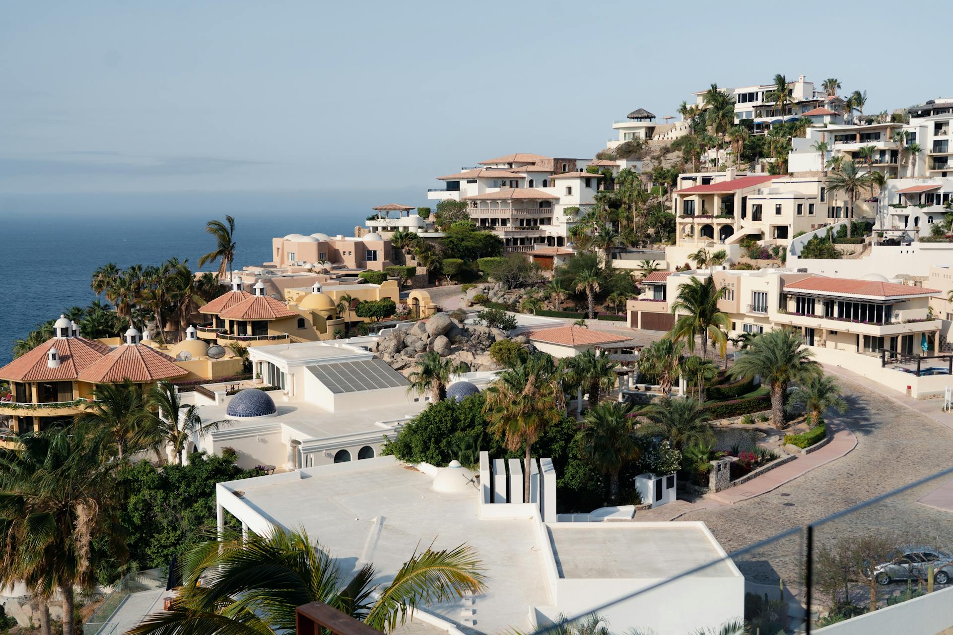 Aerial view of luxury homes along the Cabo San Lucas coastline, showcasing stunning ocean views.