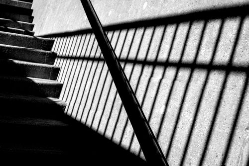 Free Intriguing shadows casting geometric patterns on a stairway in black and white. Stock Photo