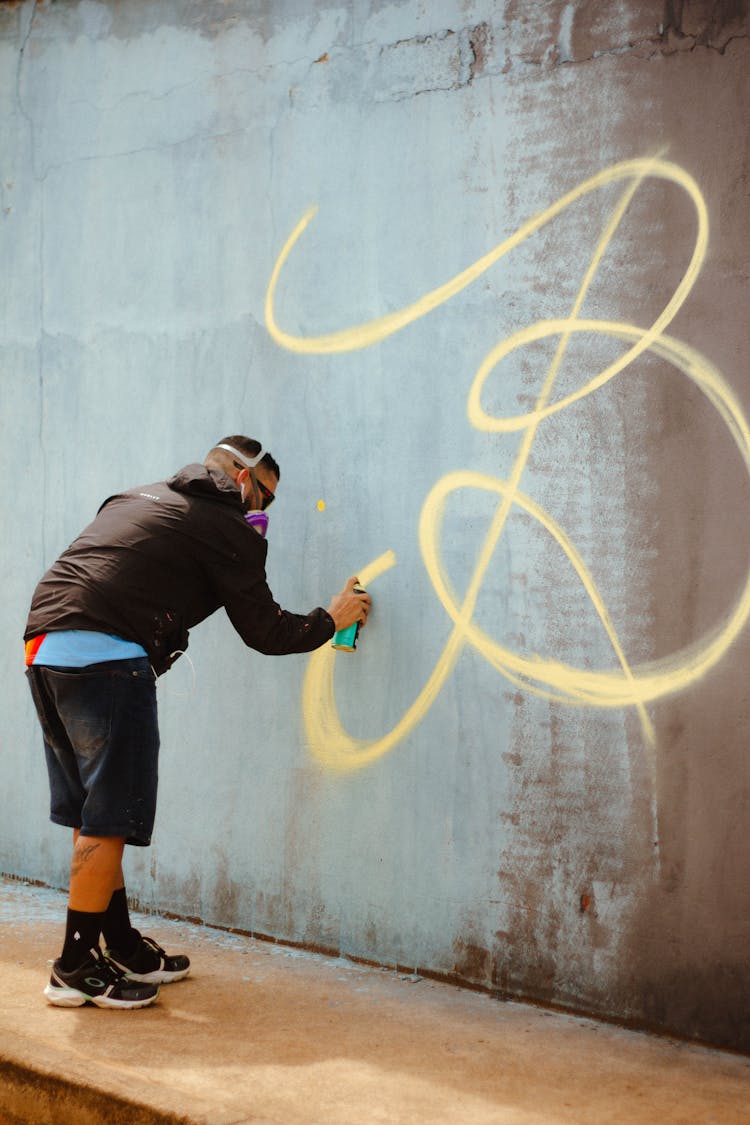 Man Drawing On Wall With Spray Bottle 