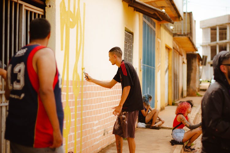 
A  Man In A Black Shirt Painting A Concrete Wall