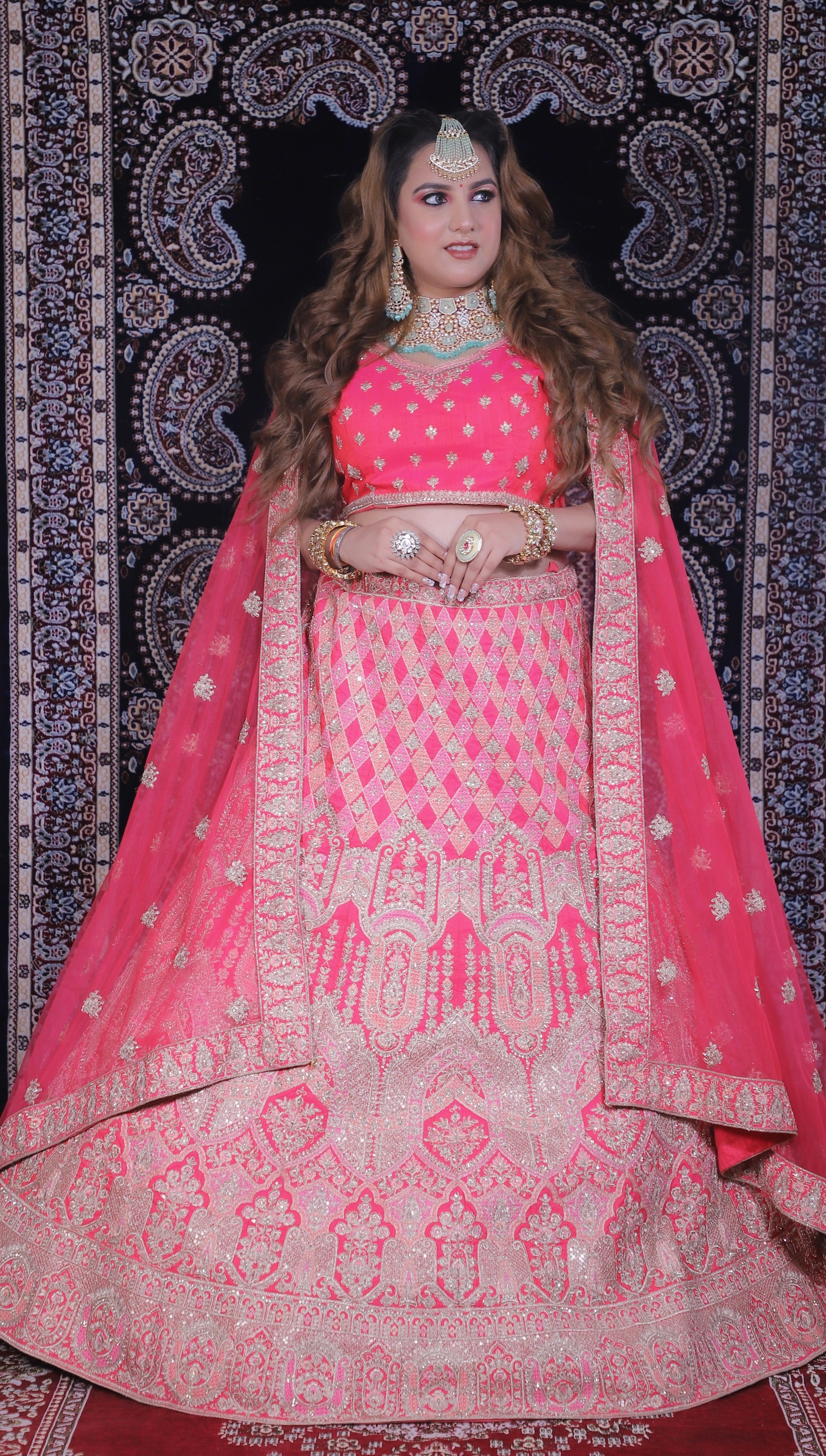 Beautiful South Asian woman in elegant pink lehenga, showcasing traditional fashion.