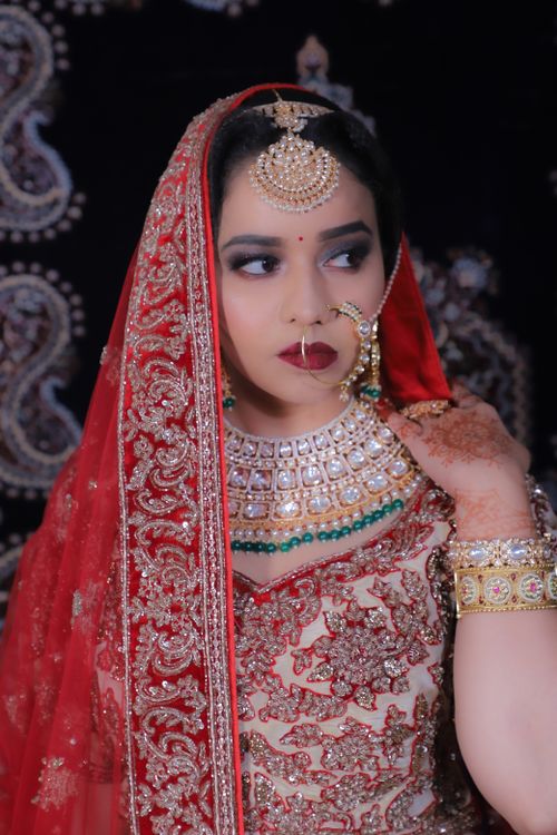 Free Captivating portrait of an Indian bride in traditional wear with intricate jewelry and vibrant red veil. Stock Photo