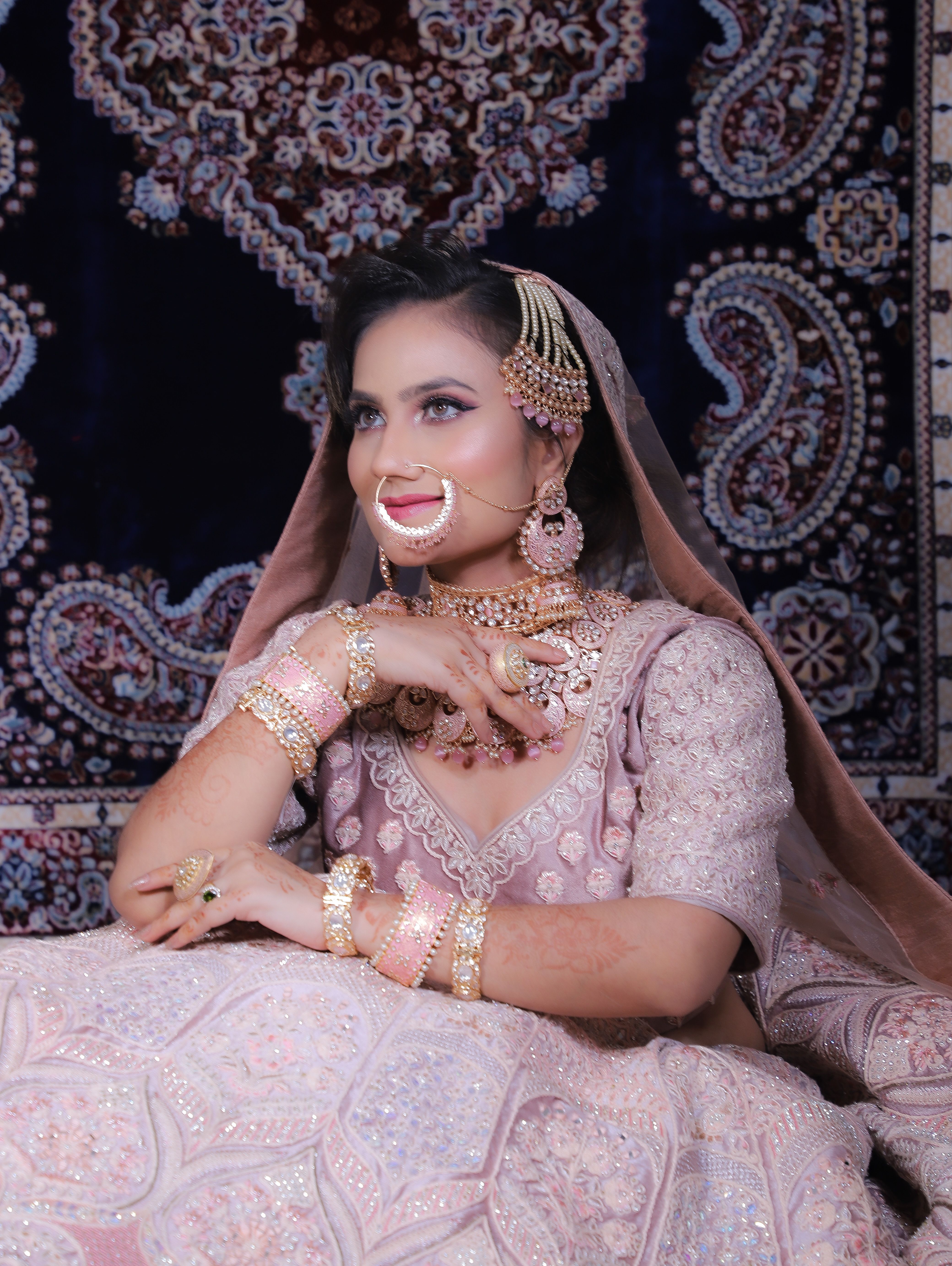 Stunning portrait of a bride in intricate jewelry and a pastel embroidered dress, showcasing cultural elegance.