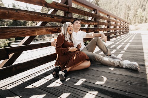 Free Couple Sitting under Wooden Fence Stock Photo