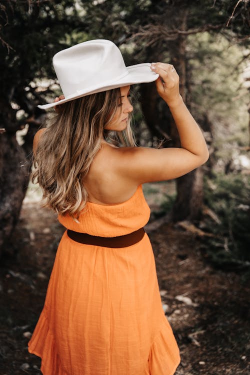 Free Woman in Orange Dress and White Hat in Forest Stock Photo