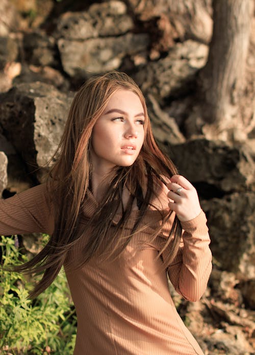 A Woman in Brown Long Sleeves Holding Her Hair