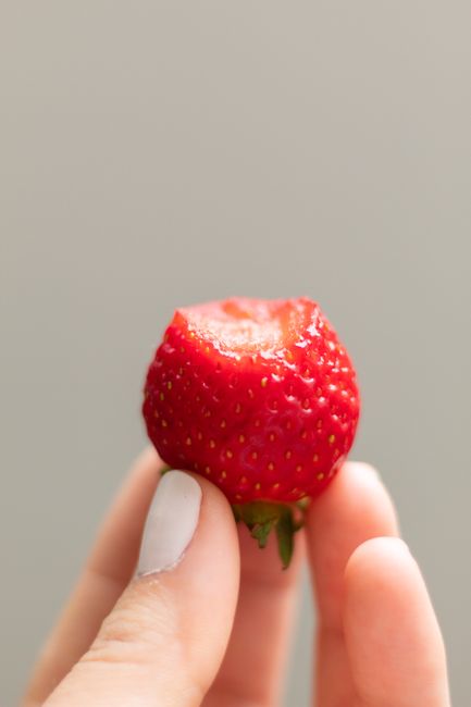 Strawberries, blueberries, and raspberries spread in a single layer on a parchment-lined baking sheet before freezing.