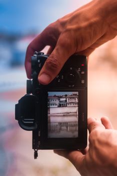 Close-up of hands holding a DSLR camera capturing a building scene.