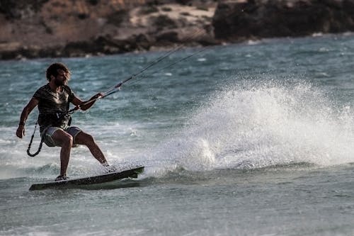 Man in Black Wetsuit Riding on Green Surfboard