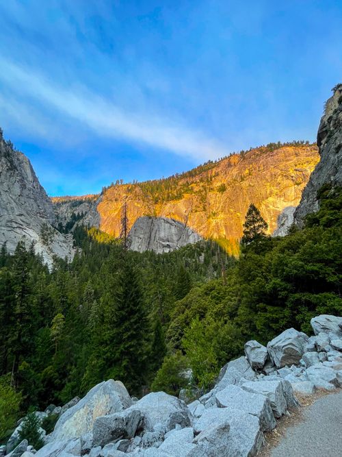 Free A breathtaking view of a mountain landscape with trees and rocks illuminated by the setting sun. Stock Photo