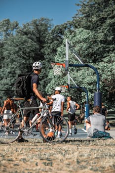 A lively basketball game in a park with cyclists watching and interacting.